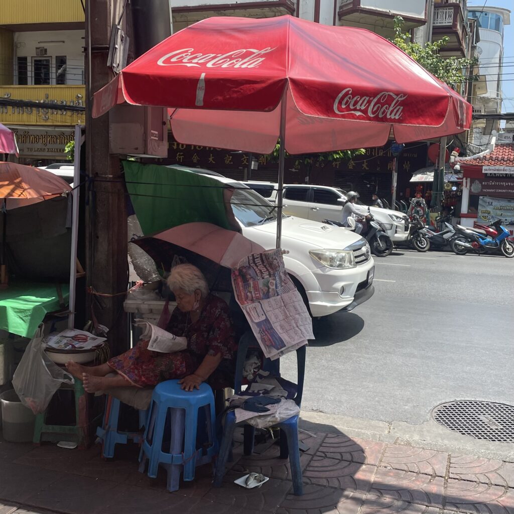 Femme thaï se reposant devant son étal sur Yaowarat Road dans le Chinatown de Bangkok